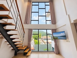 Un interior moderno con una escalera, ventanas amplias y vista a un paisaje verde.