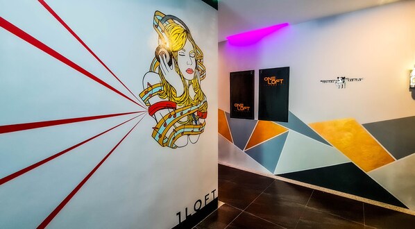 Un interior moderno con un mural colorido, diseño geométrico en la pared y señalización direccional.