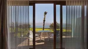 A room with a view of a deck and a palm tree, a table, and chairs. - The Setai Sea of Galilee (Ramot)