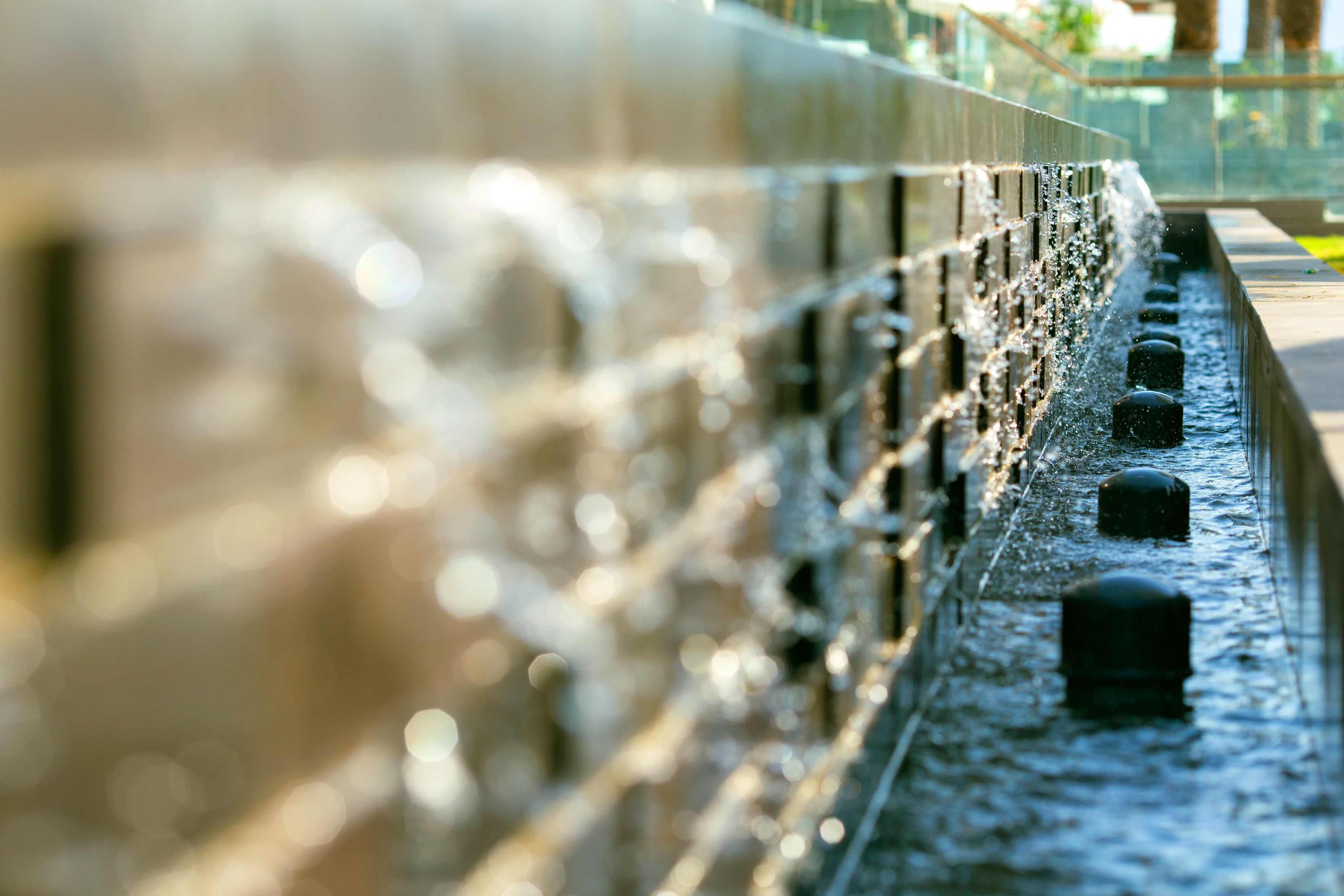 A water feature with multiple jets of water, a pathway, and bollards.
