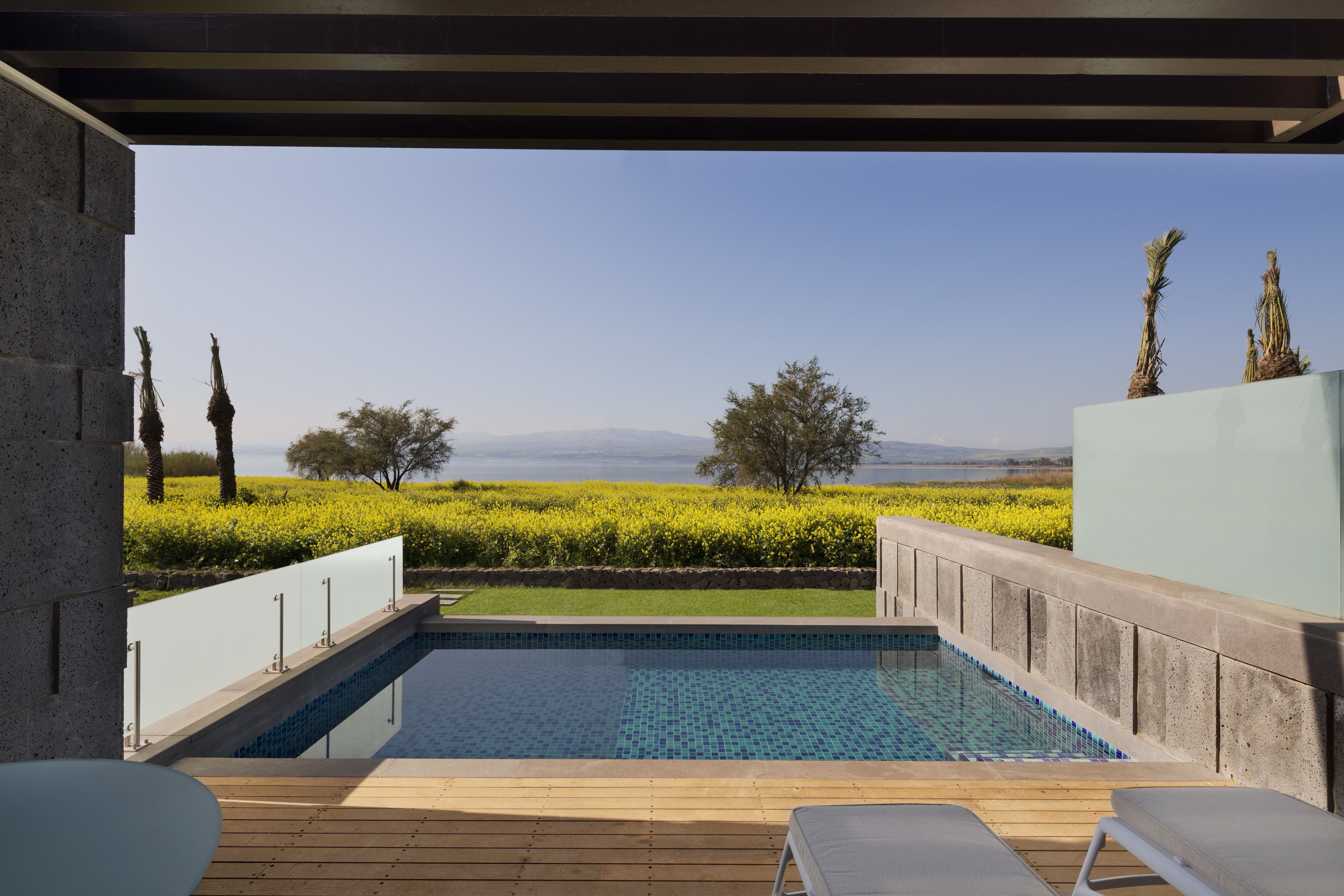 An outdoor swimming pool with a view of a green landscape and distant mountains.