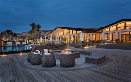 A modern resort with a pool, outdoor seating, and a well-lit building.