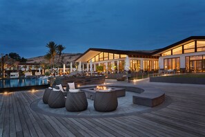 Un moderno resort con piscina, mobiliario exterior y un edificio bien iluminado.