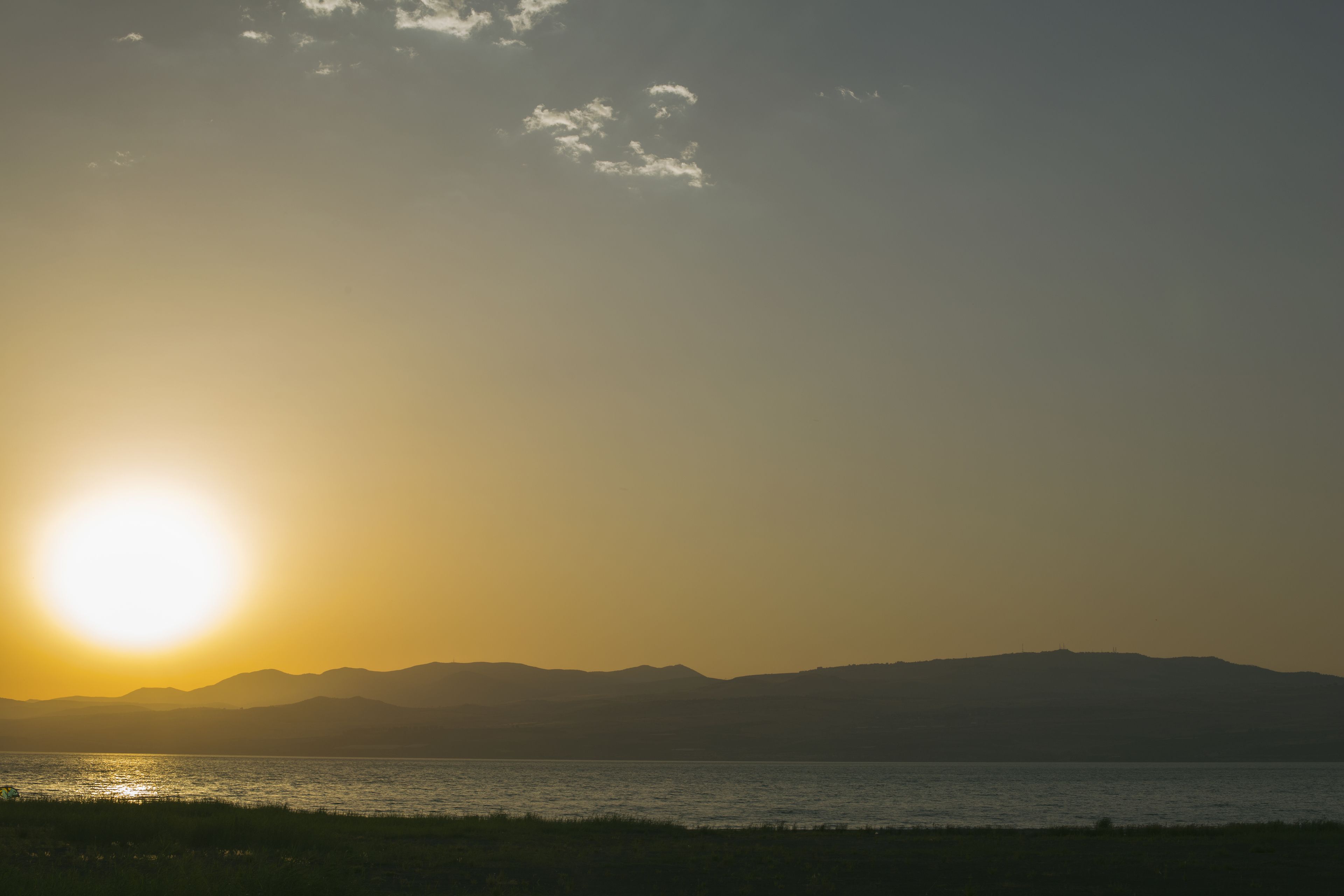 A sunset over a body of water with distant mountains.