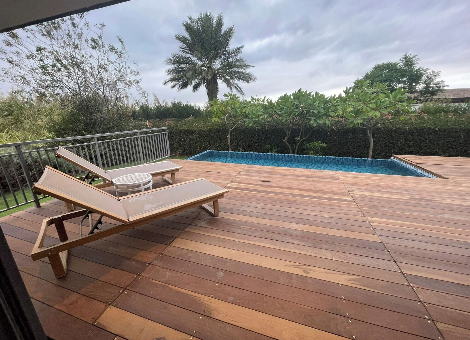 A wooden deck with lounge chairs and a swimming pool.