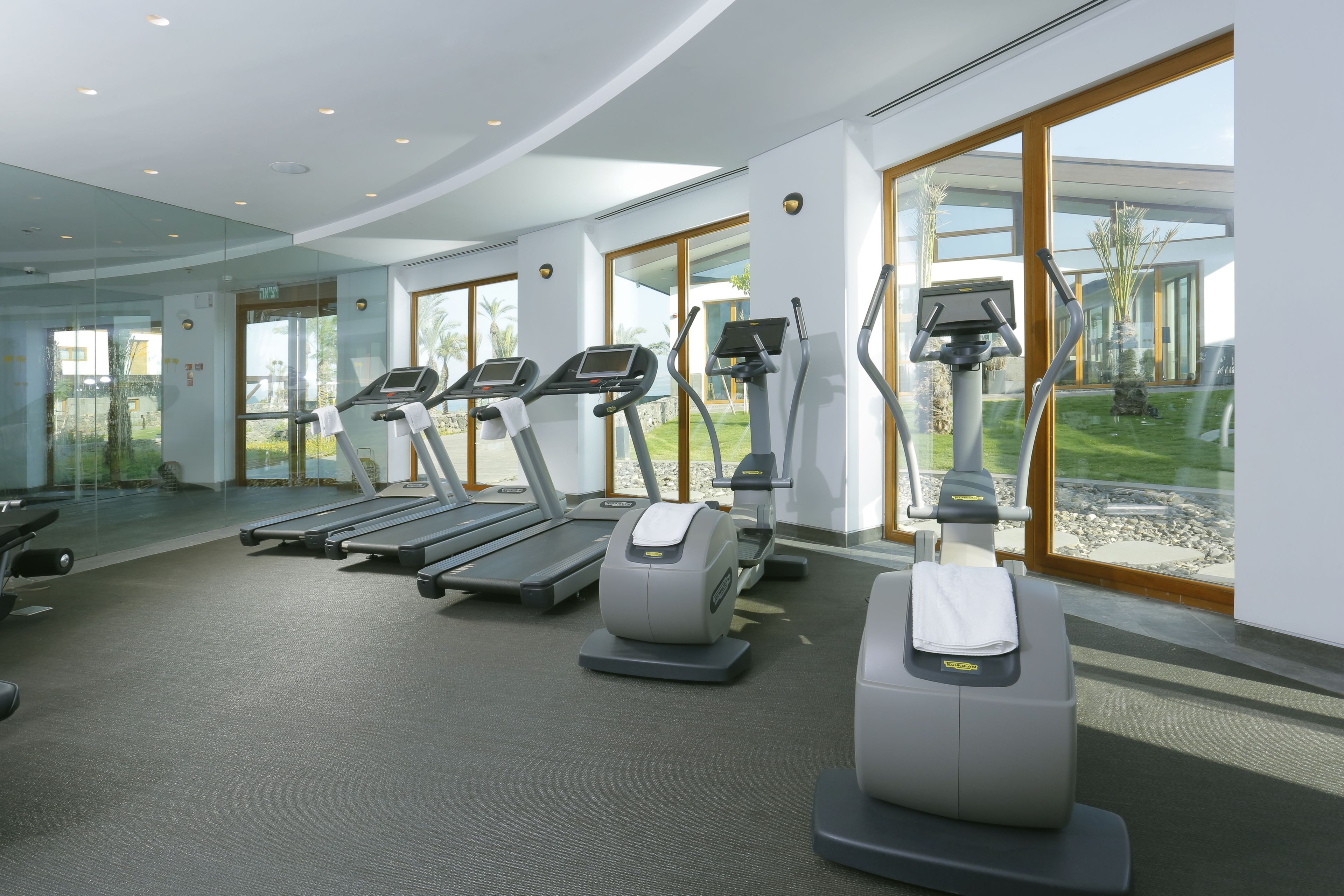 A modern gym with treadmills, elliptical machines, and a stationary bike.