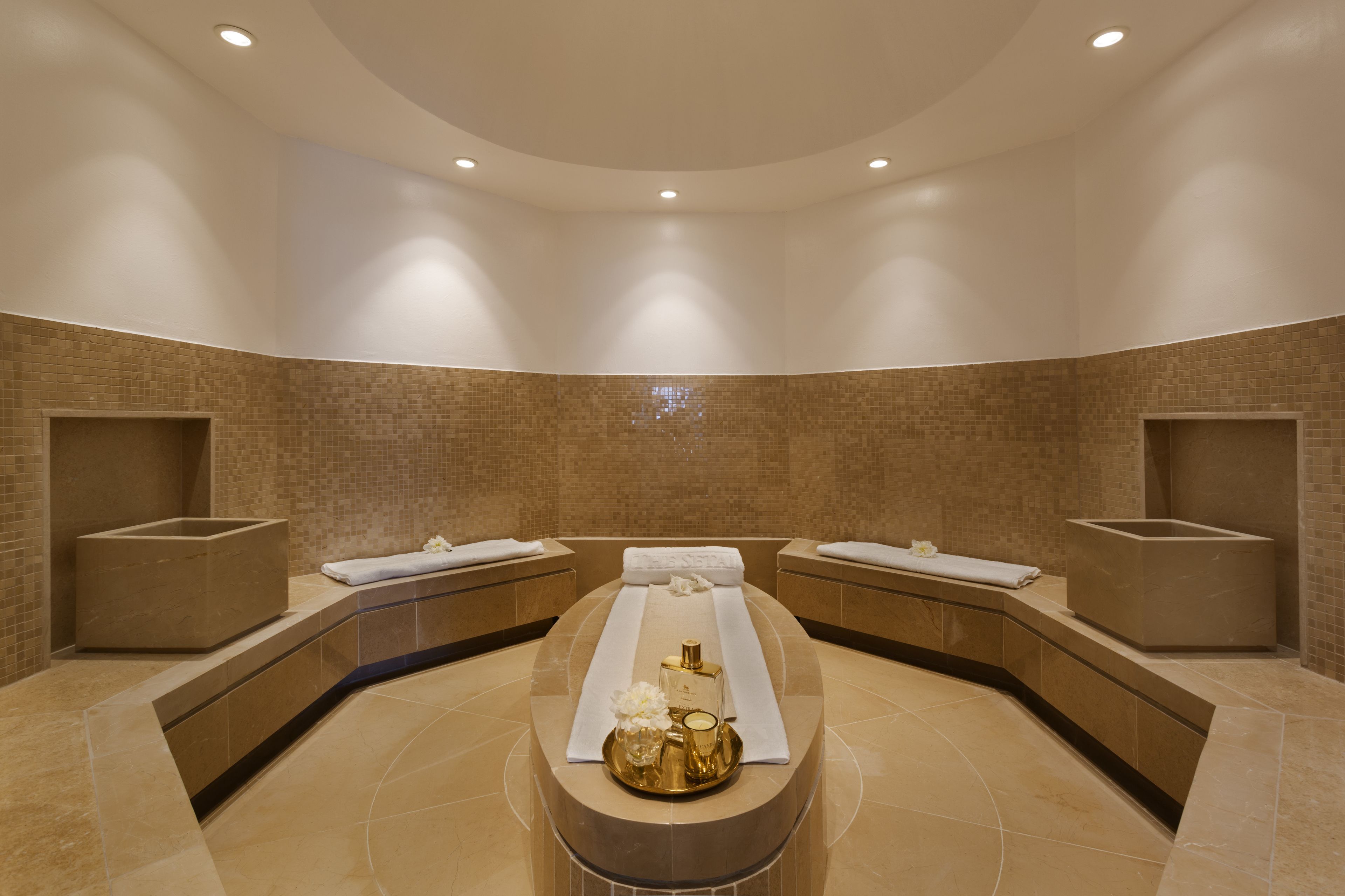 Un spa moderne doté d’un grand bain à remous central, de deux lavabos et d’un mur carrelé.