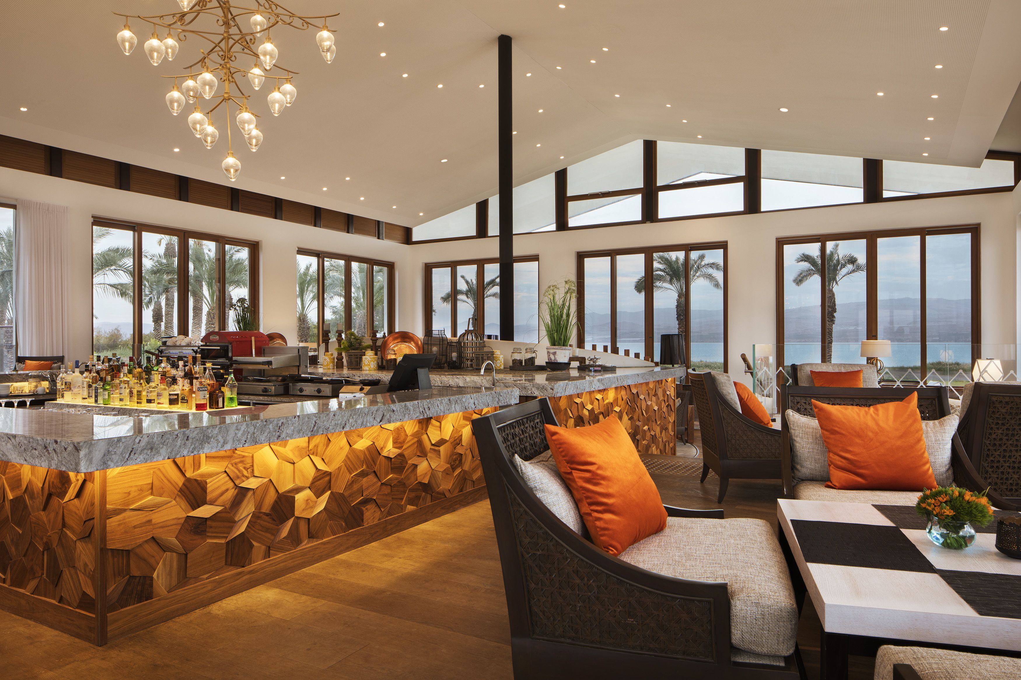 A modern kitchen with a bar area, large windows, and a view of the ocean.
