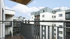 Un moderno edificio de apartamentos con balcones, una terraza de madera y un cielo despejado.