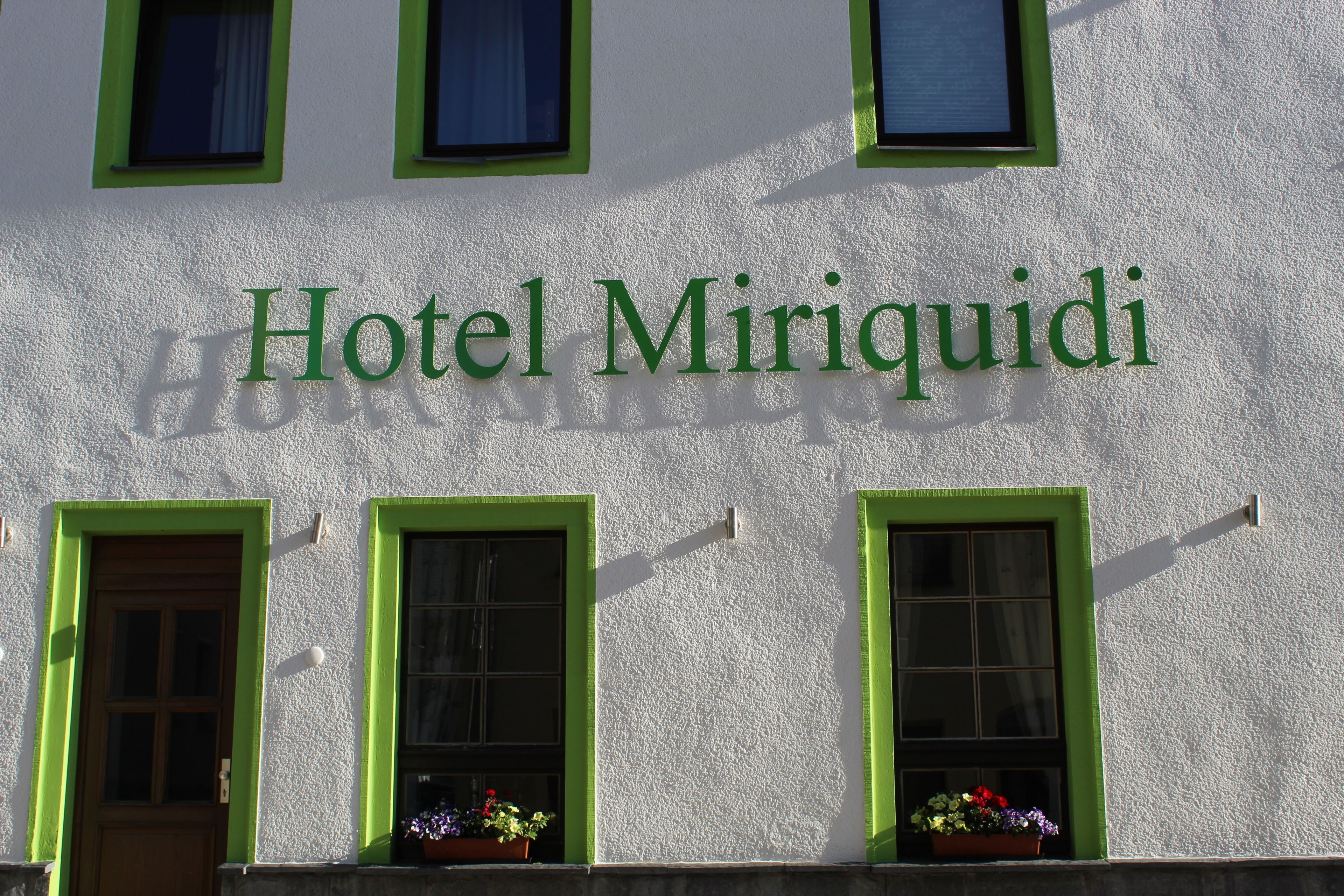 Exterior del Hotel Miriquidi, con ventanas de marco verde y un letrero encima.