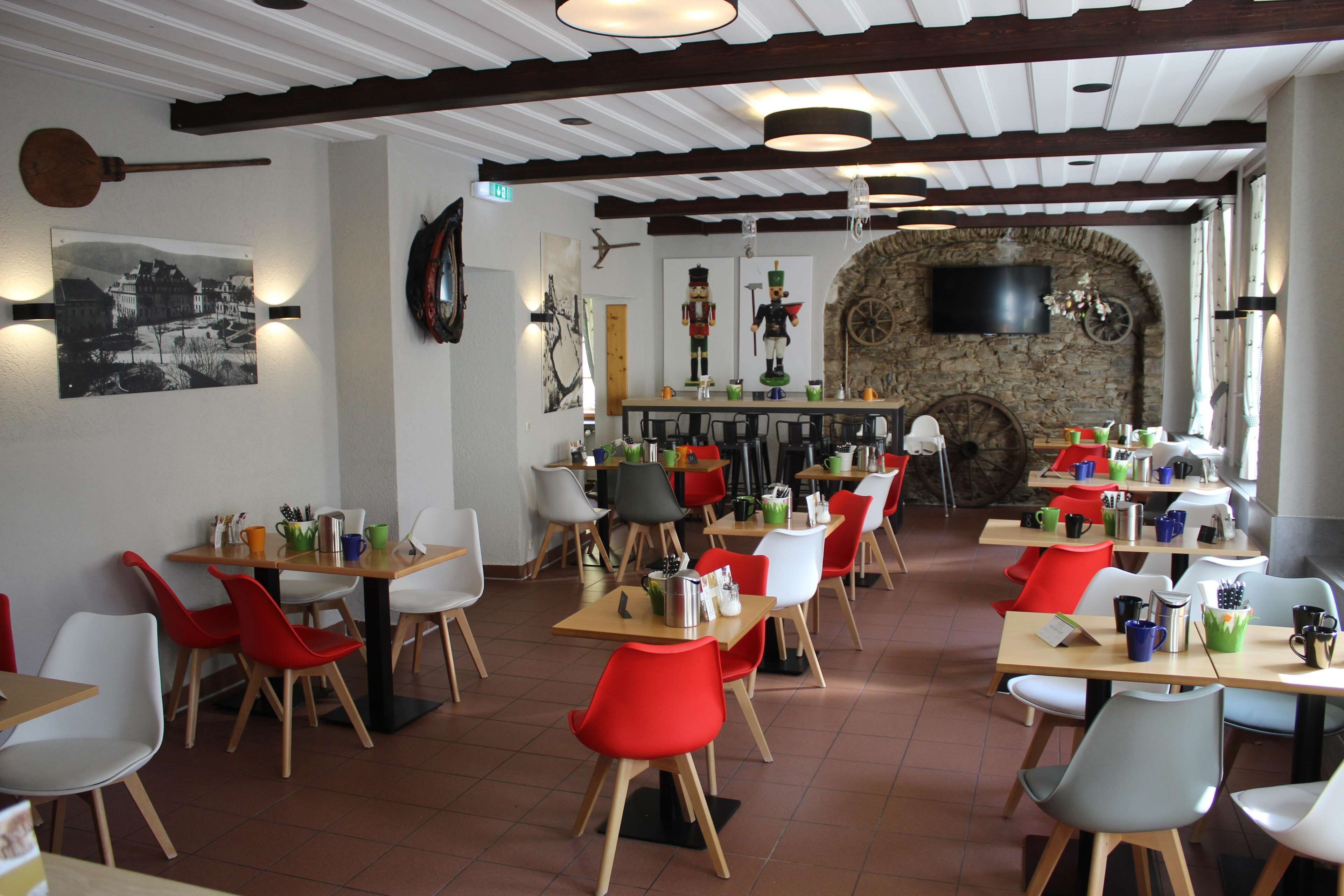 A restaurant with multiple tables and chairs, a stone wall, and a television mounted on the wall.