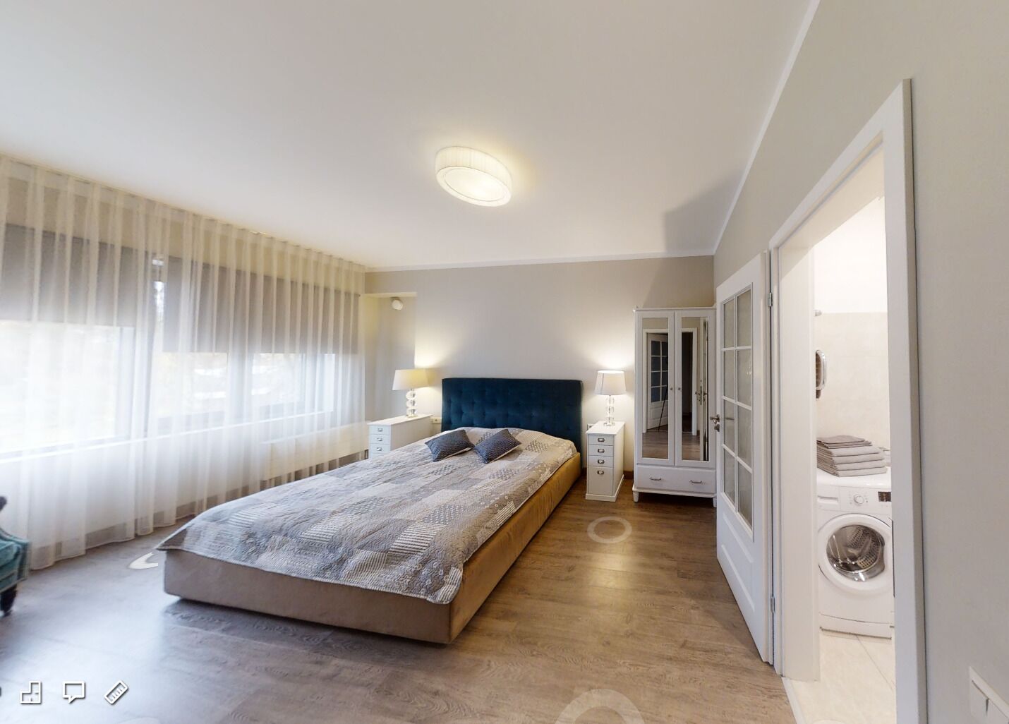 Una camera da letto moderna con un letto grande, lampade ai comodini, un armadio e una lavatrice nell'angolo.