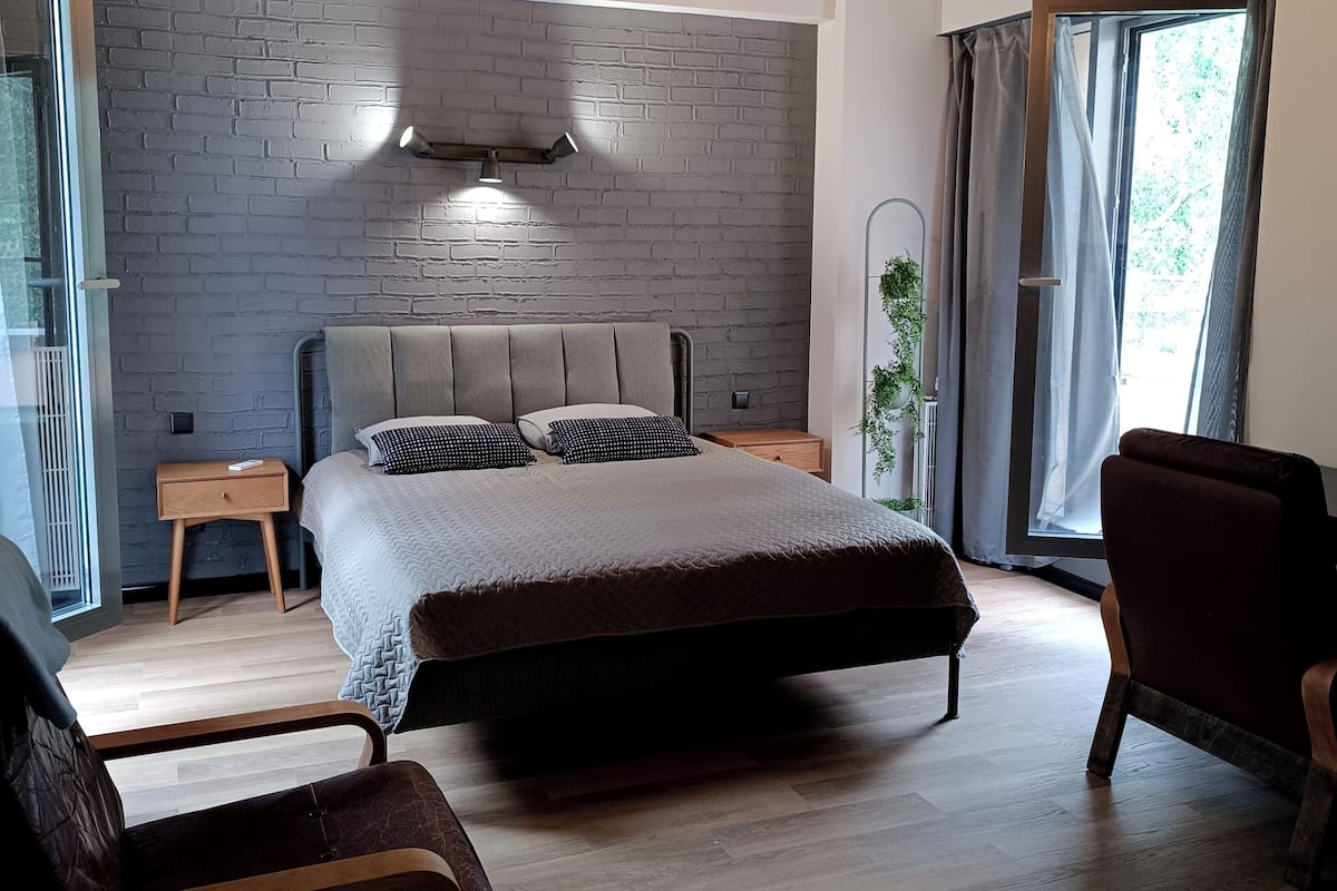 Ein modernes Schlafzimmer mit einem großen Bett, zwei Nachttischen, Holzboden und einer Wand mit Ziegeln.