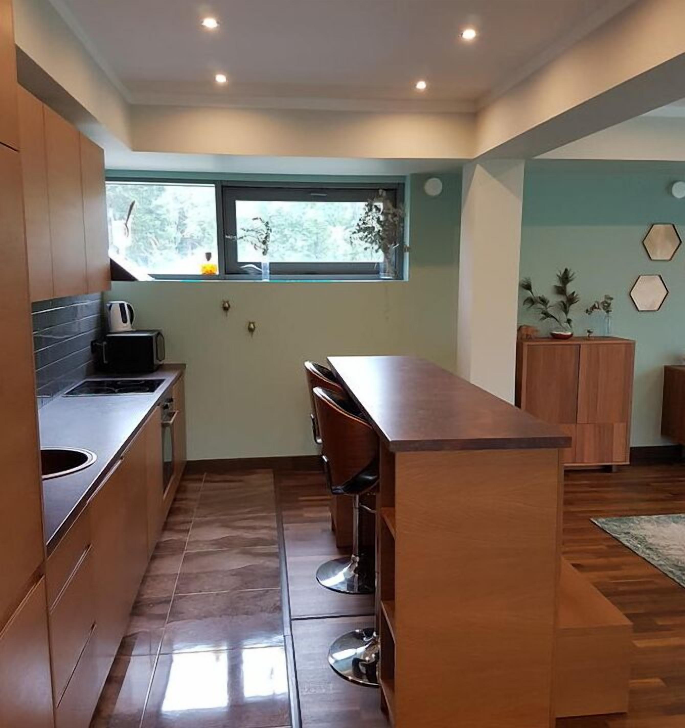 A modern kitchen with a central island, built-in appliances, and a window providing natural light.