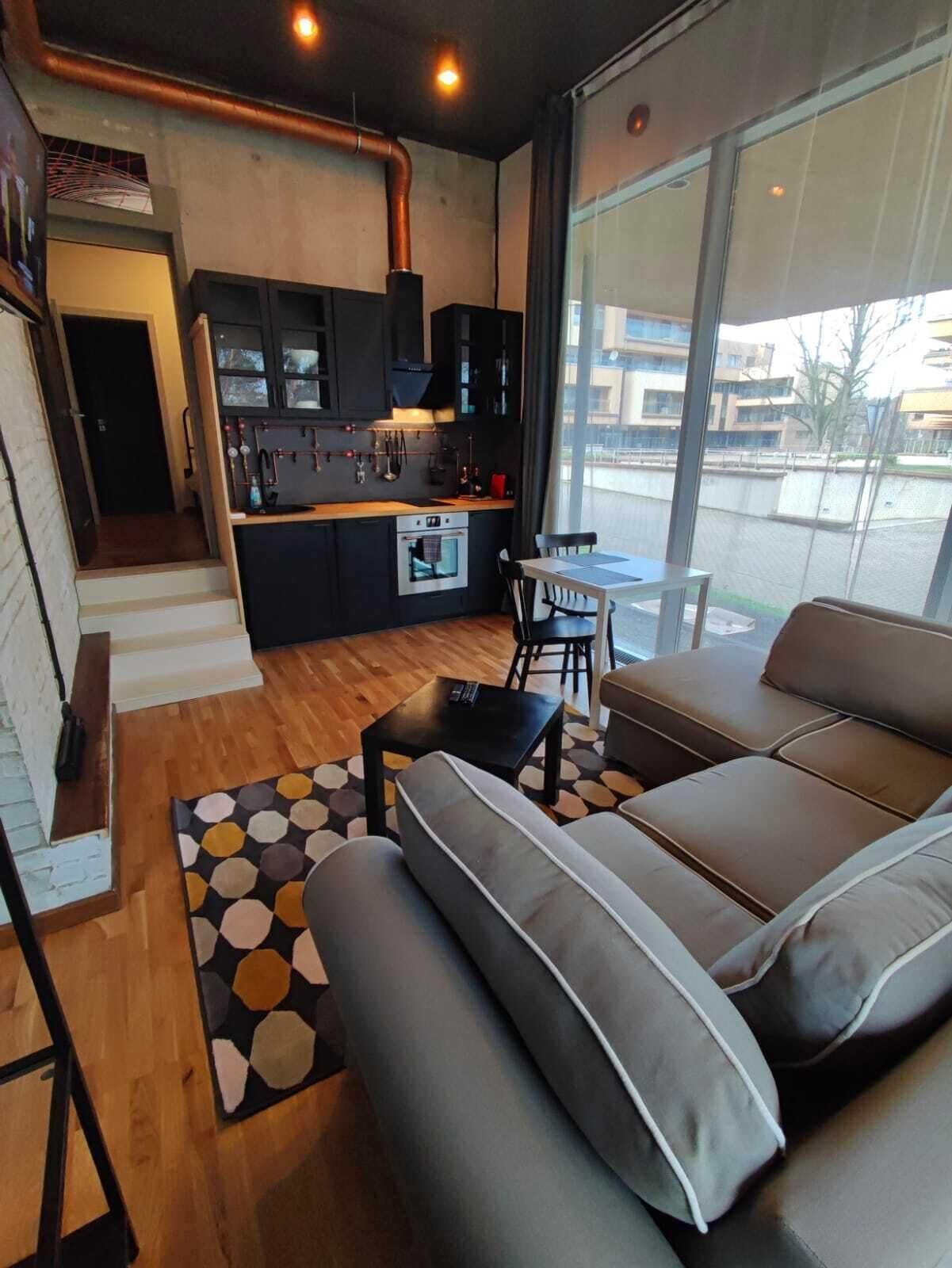 A modern apartment with a kitchen, dining area, and a large window offering a view of the city.