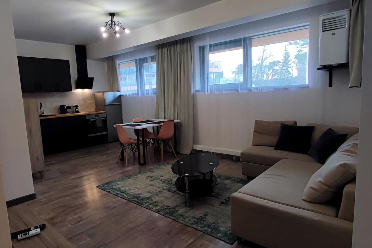 Ein modernes Wohnzimmer mit einer Couch, einem Couchtisch und einem Essbereich mit Stühlen und einem Tisch.