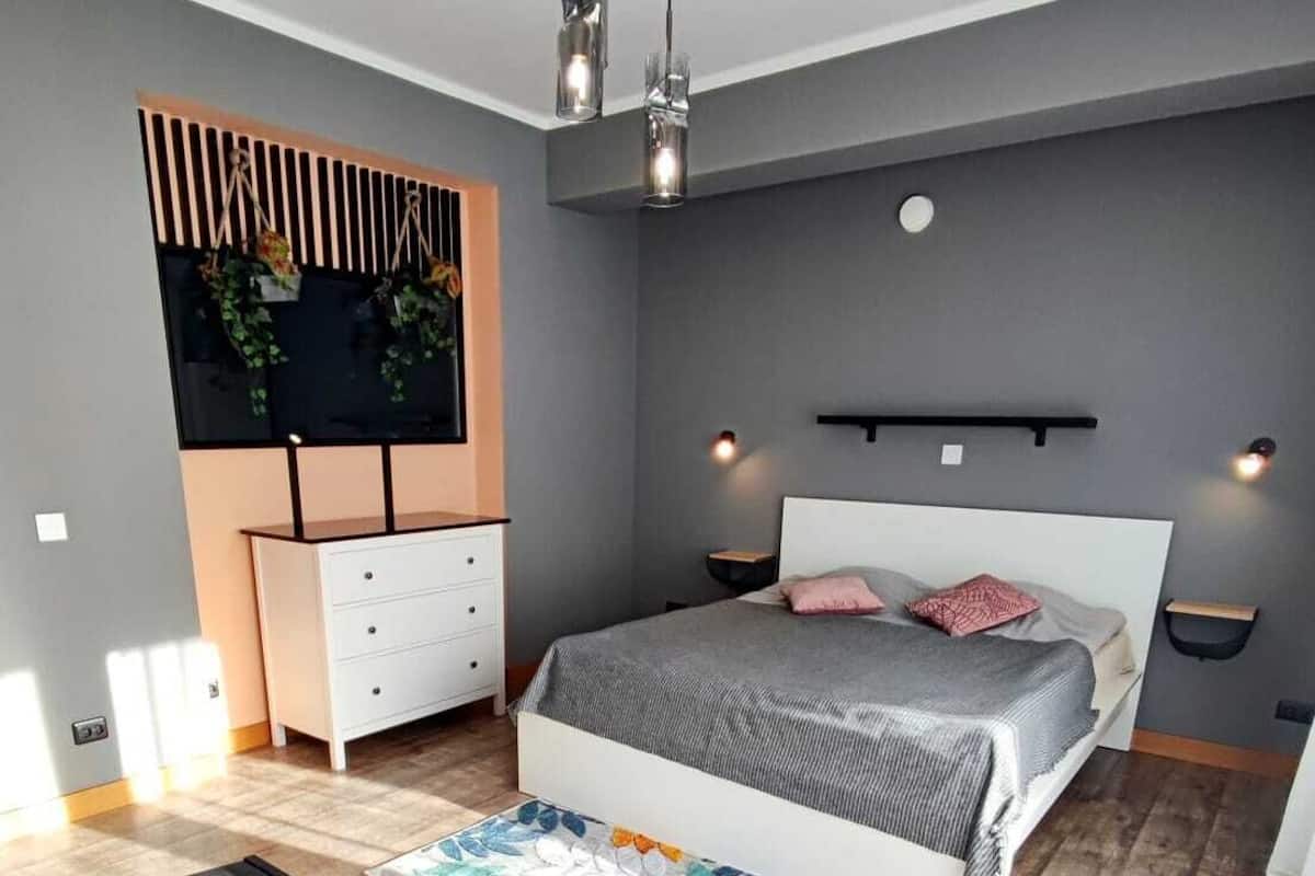 Ein modernes Schlafzimmer mit Bett, Nachttischen, einem Schminktisch und einem Schreibtisch mit Stuhl.