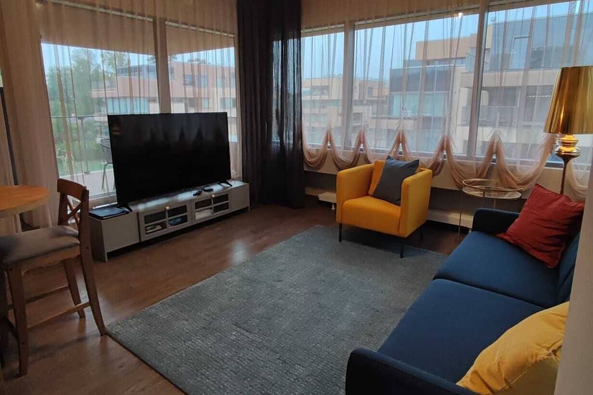 Ein Wohnzimmer mit Flachbildfernseher, Sofa, Sessel und einem kleinen Tisch.