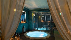 A spa room with a hot tub, wooden flooring, and a decorative window. - Relais Sassa al Sole (San Miniato)