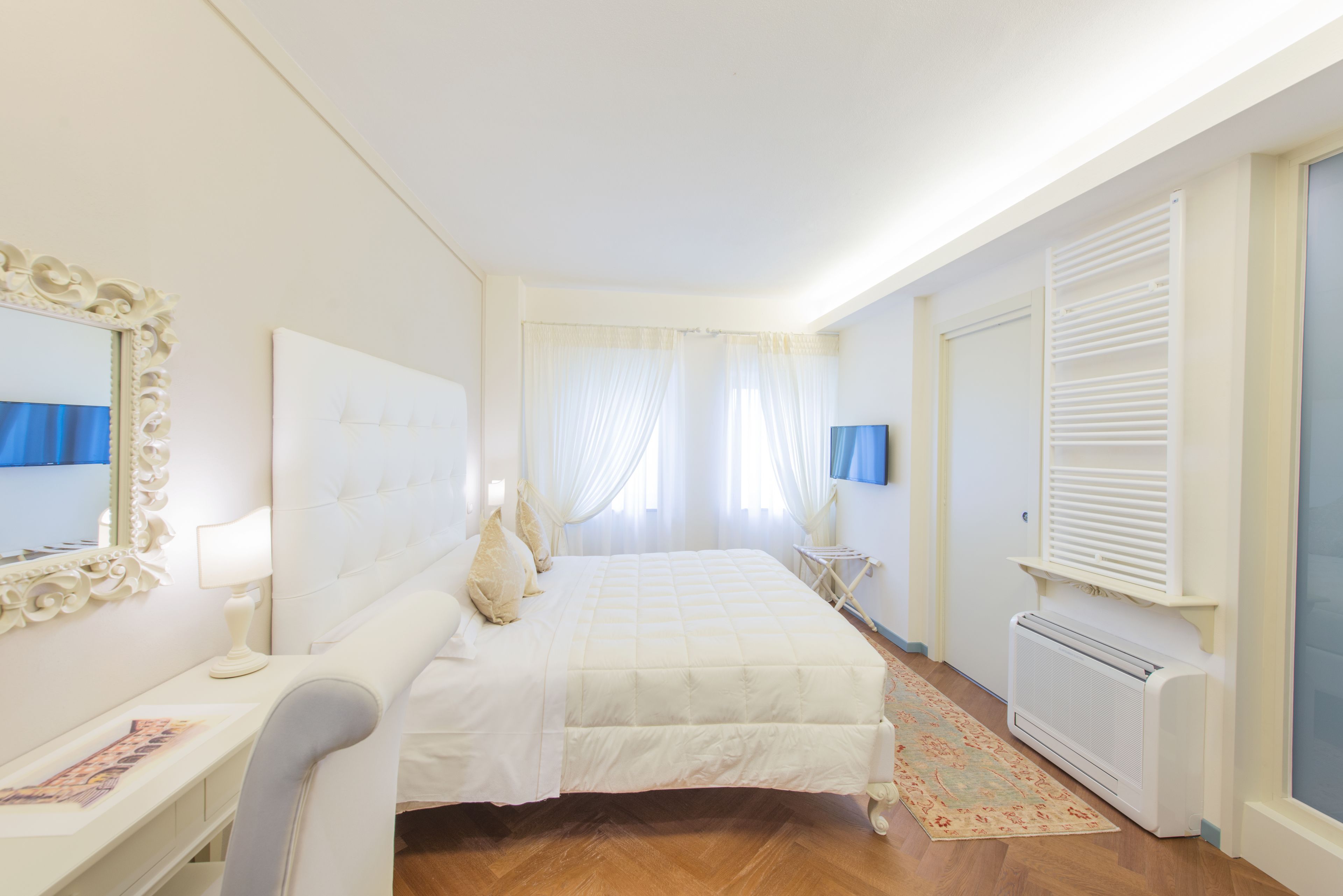 A bedroom with a bed, bedside table, lamp, and a radiator.