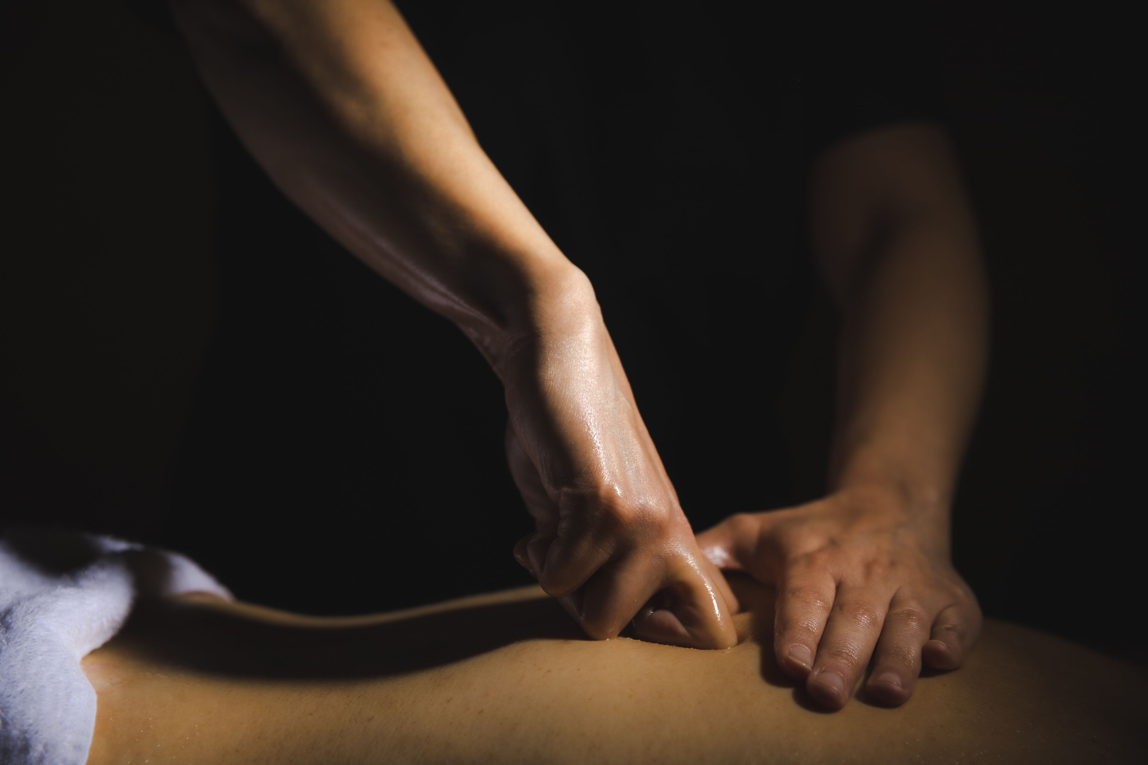 A close-up of hands performing a massage on a person's back.