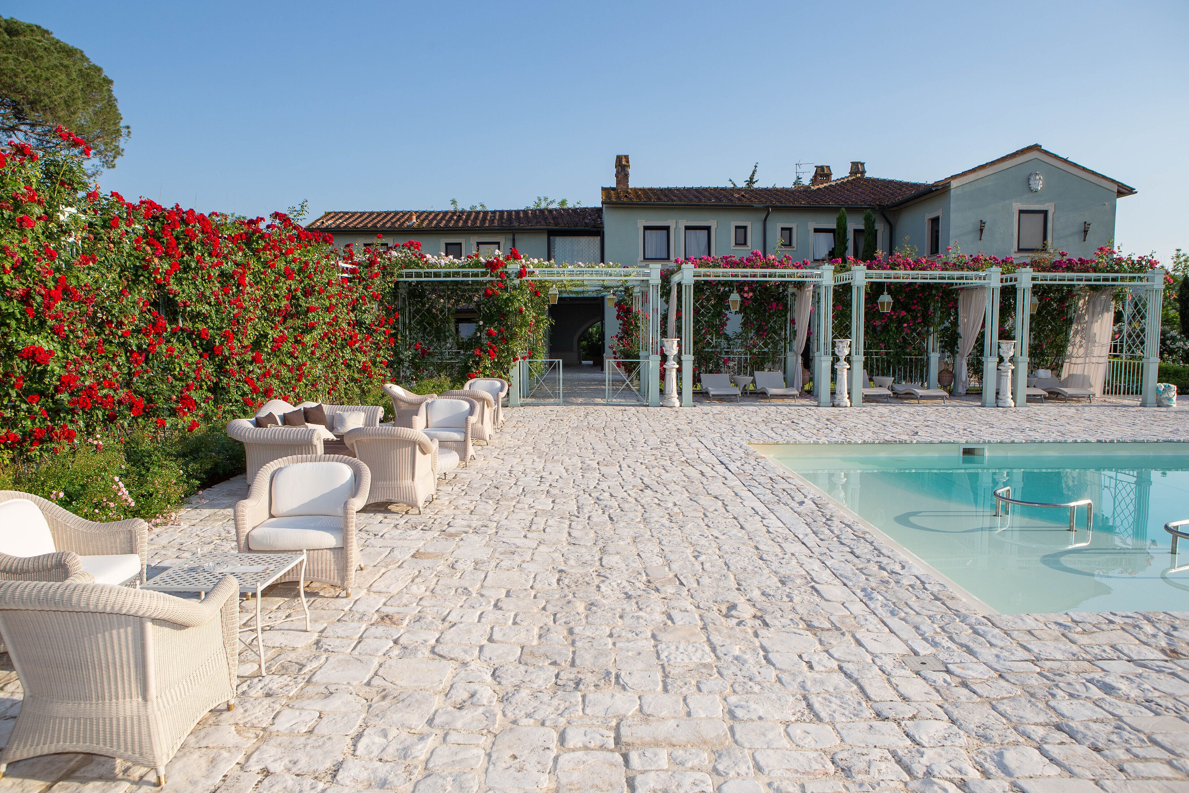 A courtyard with a pool, wicker furniture, and a building with a garden.