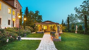 A well-maintained garden with a stone pathway leading to a house with a tiled roof and a porch. - Relais Sassa al Sole (San Miniato)