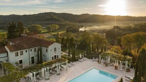 A villa with a swimming pool, surrounded by lush greenery and hills. - Relais Sassa al Sole (San Miniato)