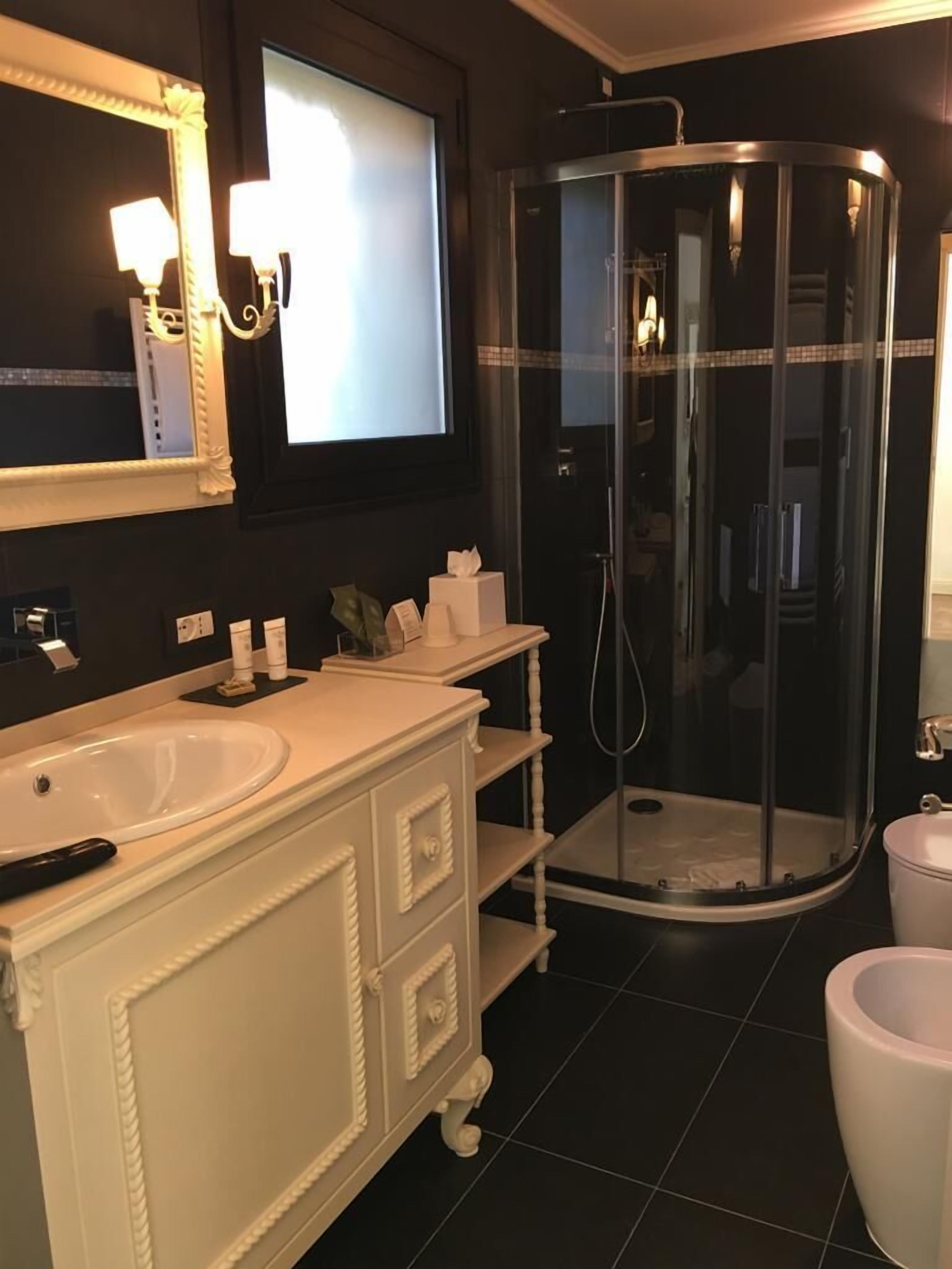 A bathroom with a white vanity, a large mirror, a shower enclosure, and a toilet.
