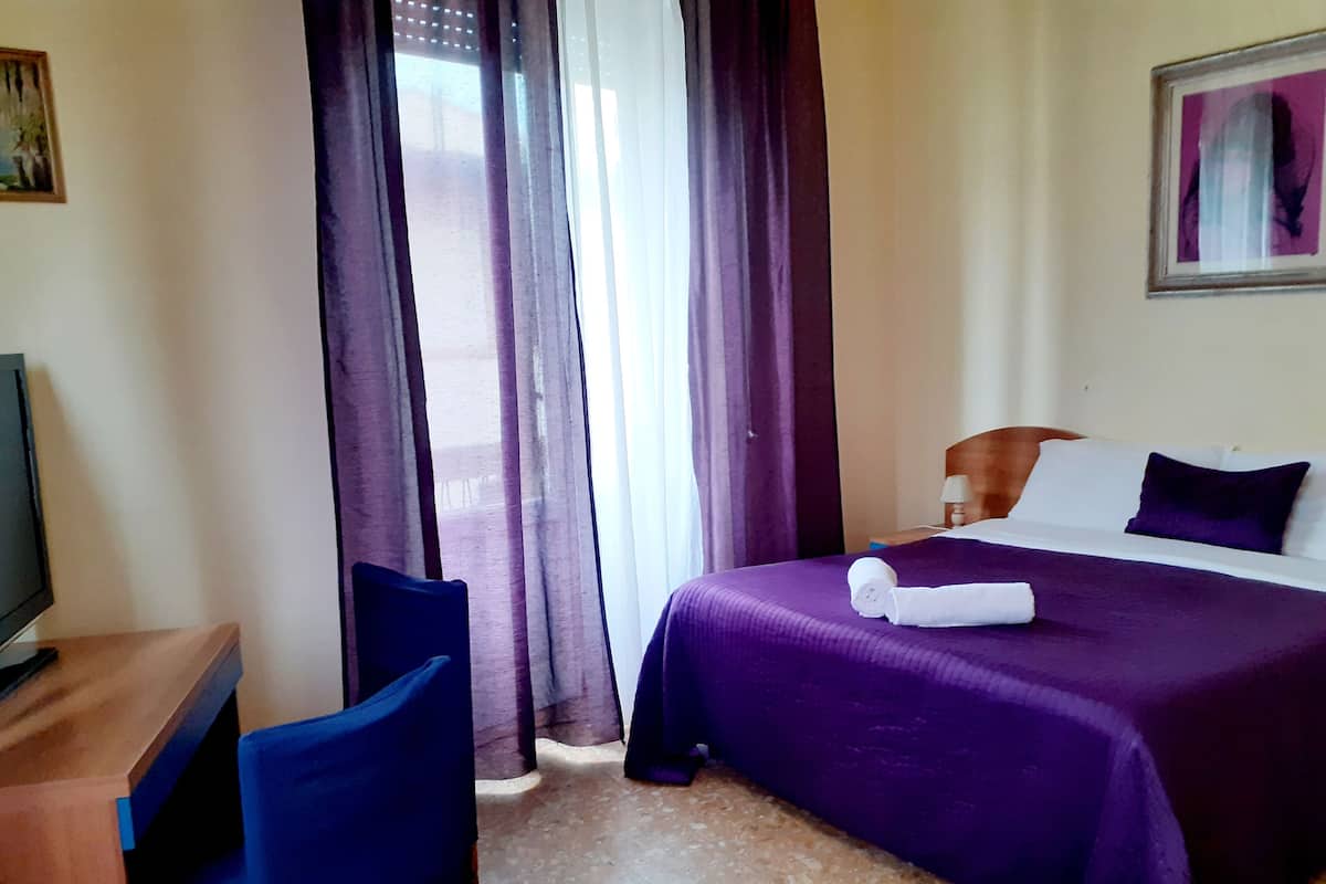 Une chambre d’hôtel équipée d’un lit, d’un bureau, d’une chaise et d’un téléviseur.