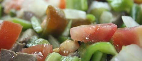 A close-up of a chopped salad with tomatoes, green peppers, and onions.