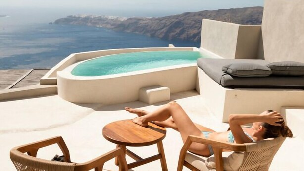 A rooftop terrace with a hot tub, lounge chairs, and a view of the sea.