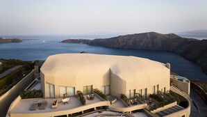 A modern building with a curved roof overlooking a coastal landscape.