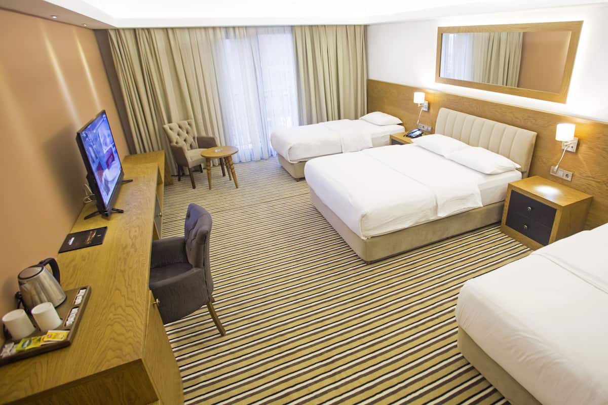 A hotel room with two beds, a desk with a computer, a chair, a small table, and a TV.