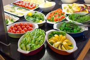 Ein reichhaltiges Buffet mit verschiedenen Speisen, darunter Salate, Früchte und Gemüse.