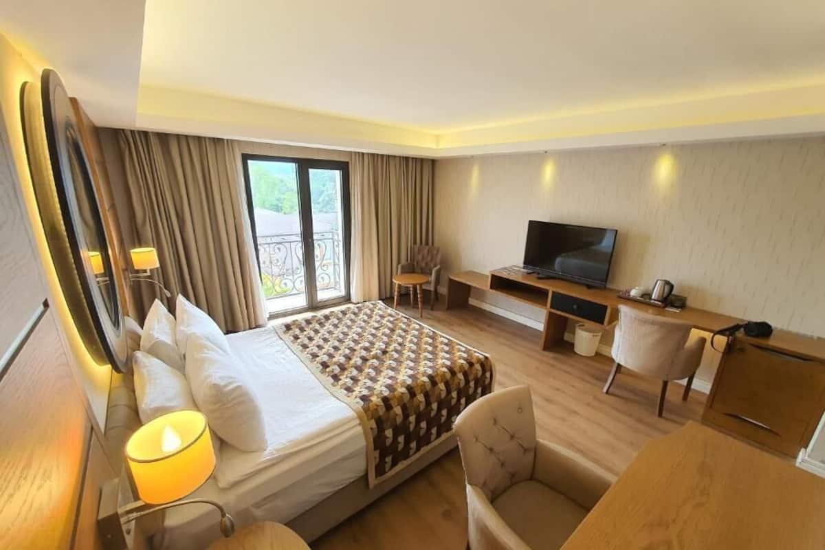 A hotel room with a bed, a TV, a desk, and a chair.