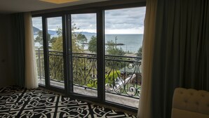 Une chambre d’hôtel dotée d’un grand balcon, d’un sol à motifs et offrant une vue sur la mer et les montagnes.
