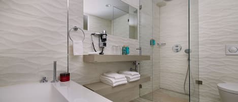Un baño moderno con cabina de ducha de vidrio, un espejo grande y un mueble de tocador con toallero.