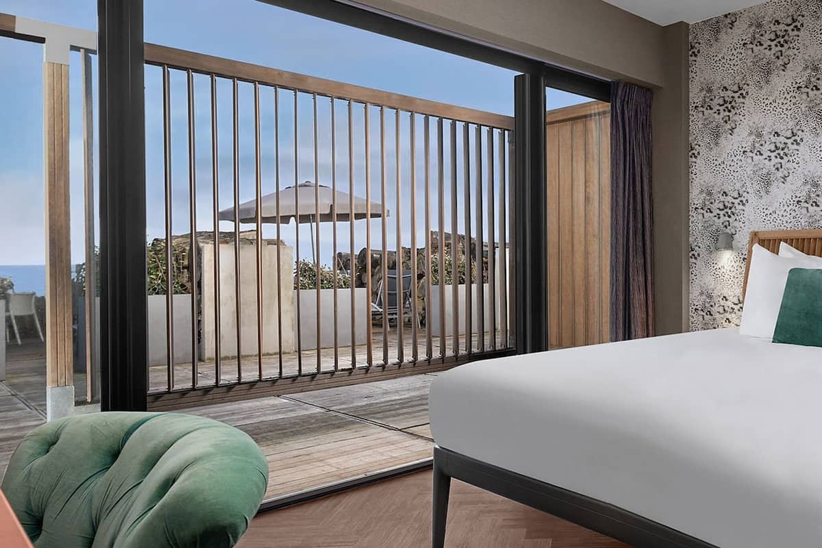 Een slaapkamer met een groot bed, uitzicht op de omgeving en een balkon met een hekwerk.