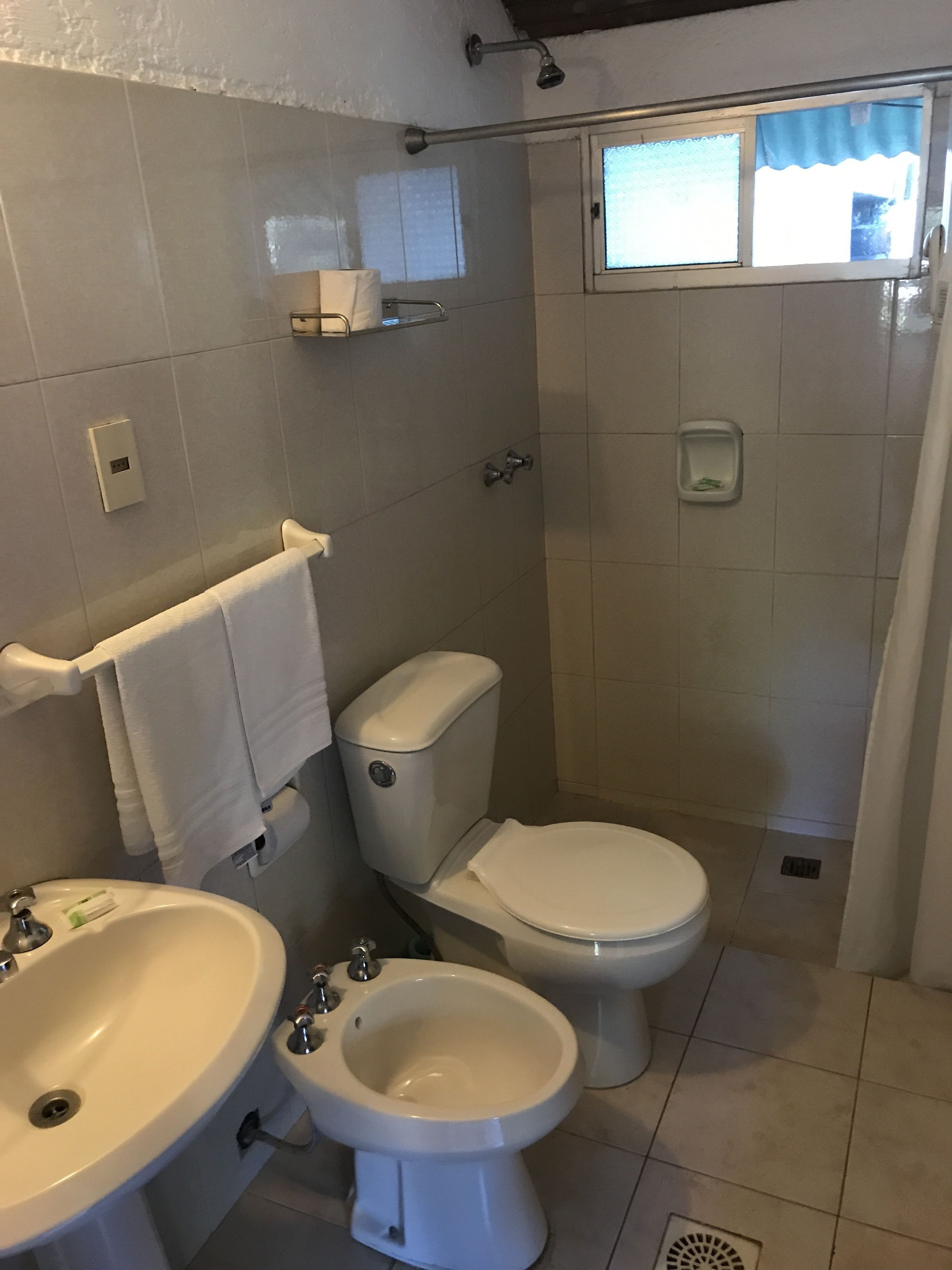 A bathroom with a toilet, bidet, sink, and shower.
