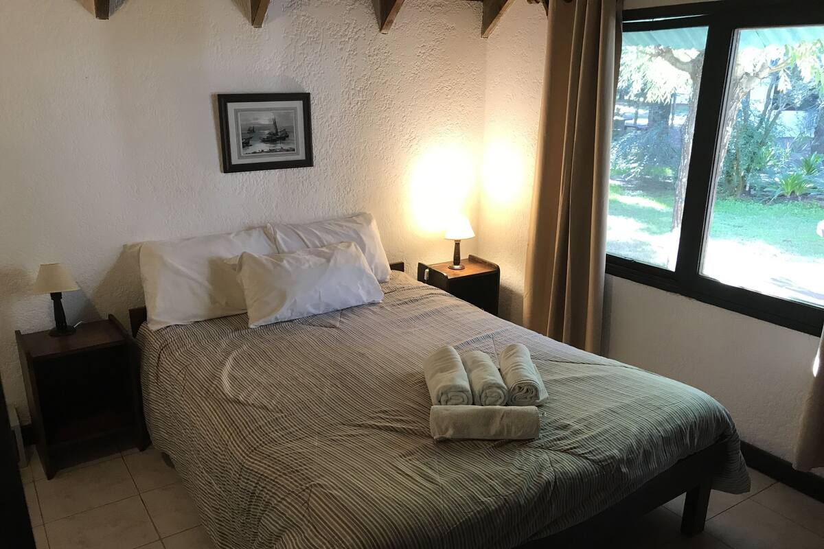 A neatly made bed with striped bedding, a bedside lamp, and a framed picture on the wall.