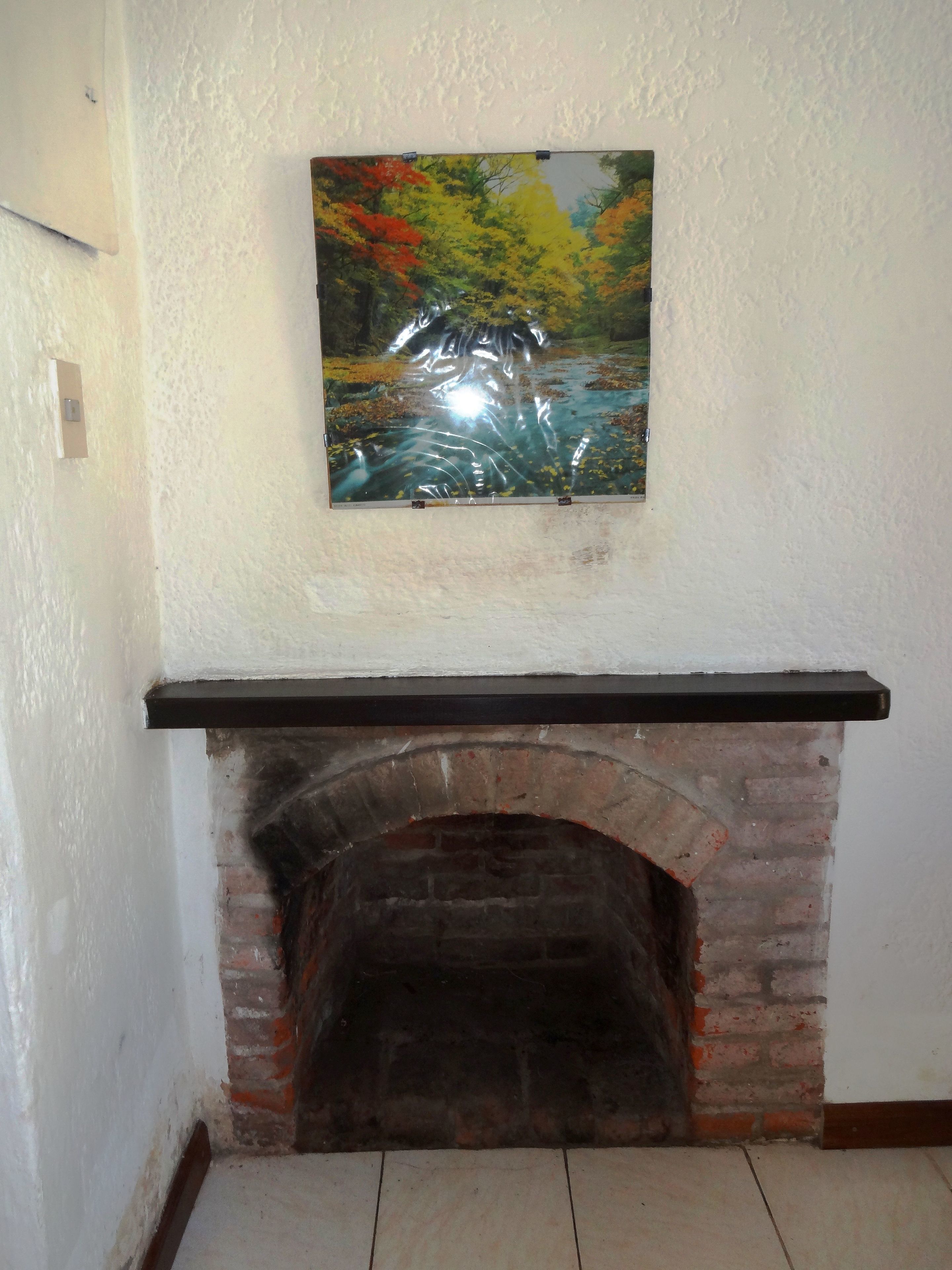 A fireplace with a brick arch and a black mantel.