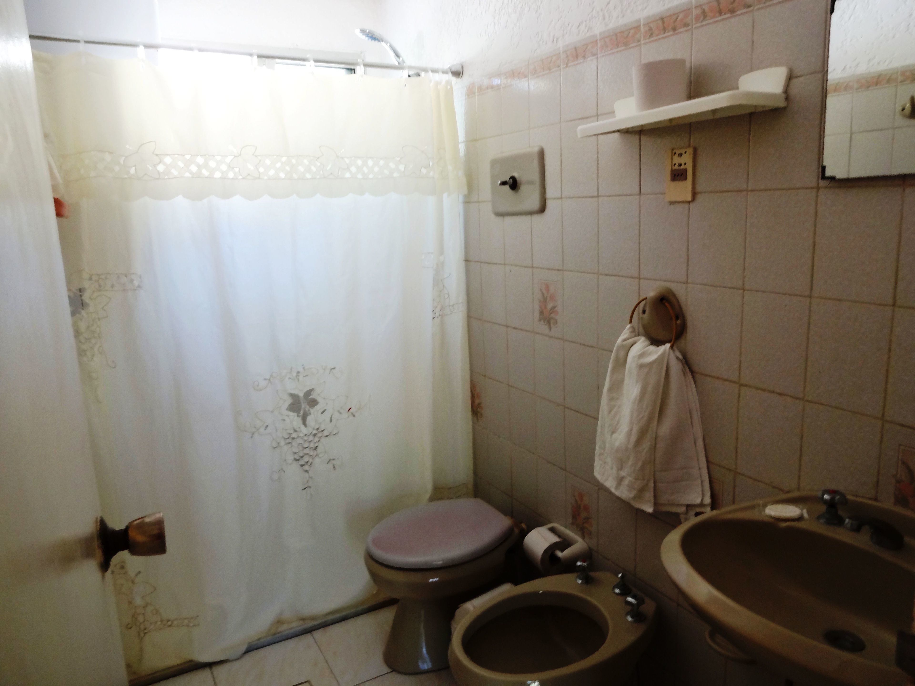 A small, basic bathroom with a toilet, sink, and shower curtain.