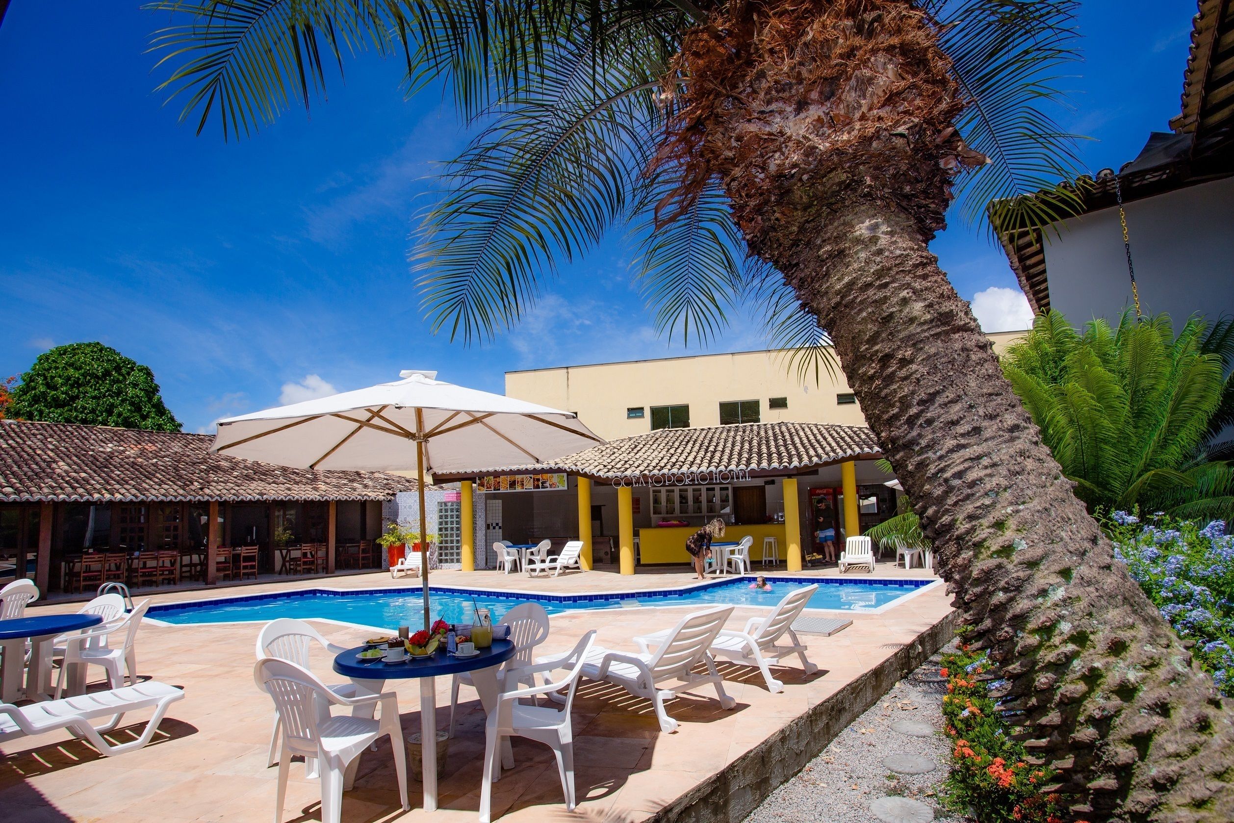 Una piscina al aire libre, sombrillas, sillones reclinables de piscina