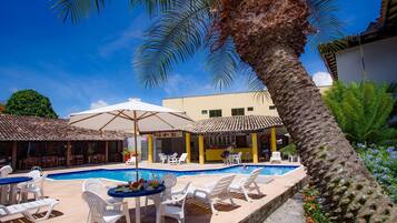 Una piscina al aire libre, sombrillas, sillones reclinables de piscina