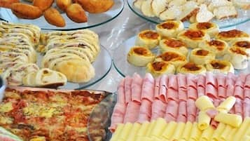 Un bufé con diversos alimentos, incluyendo pan, bollería y embutidos.