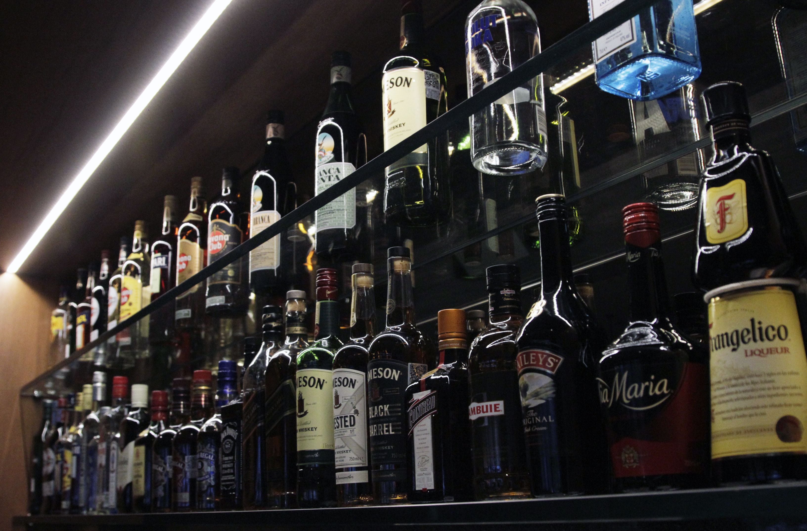 A bar shelf stocked with various liquor bottles.
