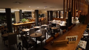 Un restaurant moderne avec des tables et des chaises rondes, un bar et un espace détente avec des canapés et des fauteuils.