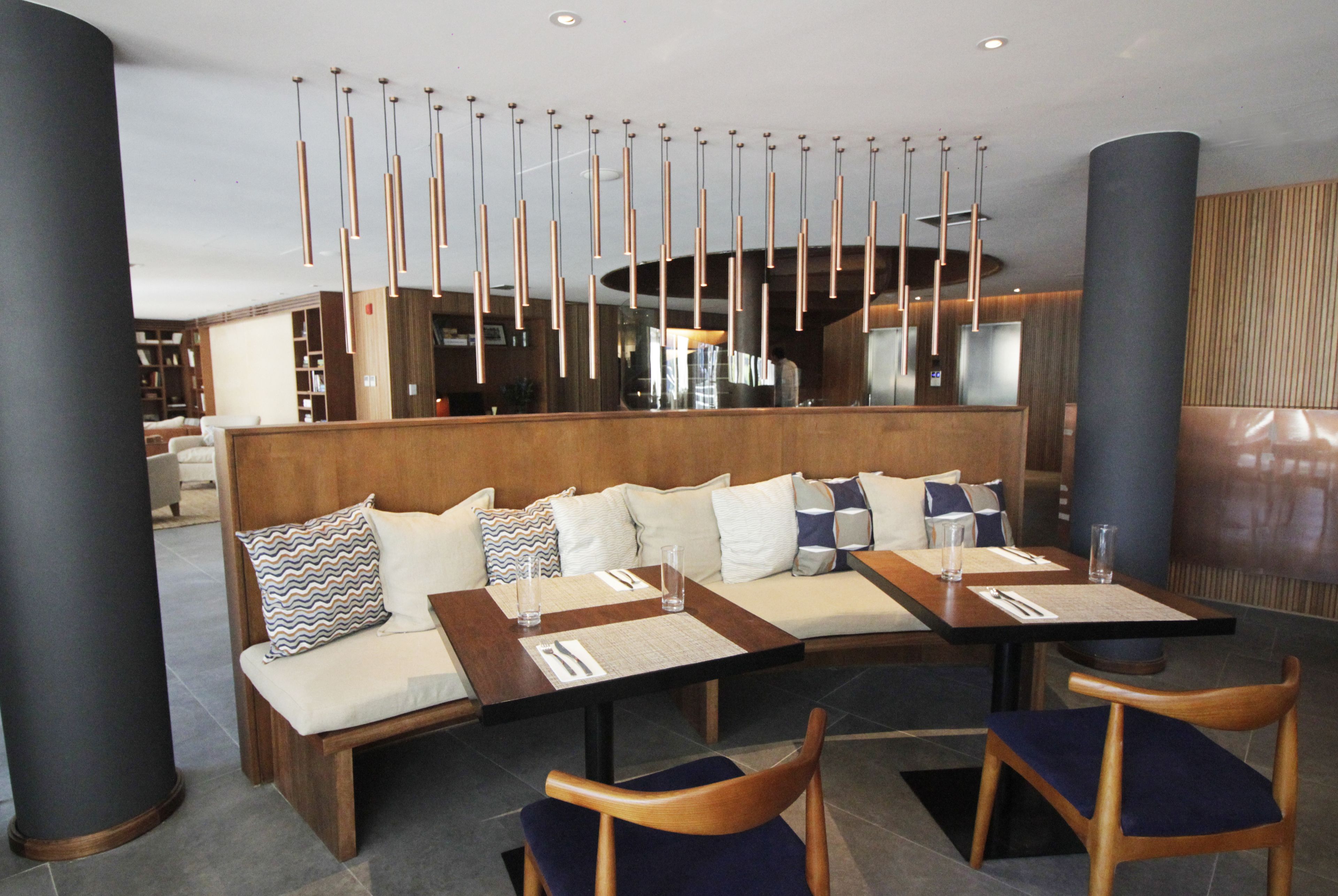 A modern dining area with a long wooden bench and a table, surrounded by chairs.