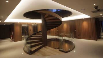 A modern spiral staircase with glass railings in a well-lit interior space.